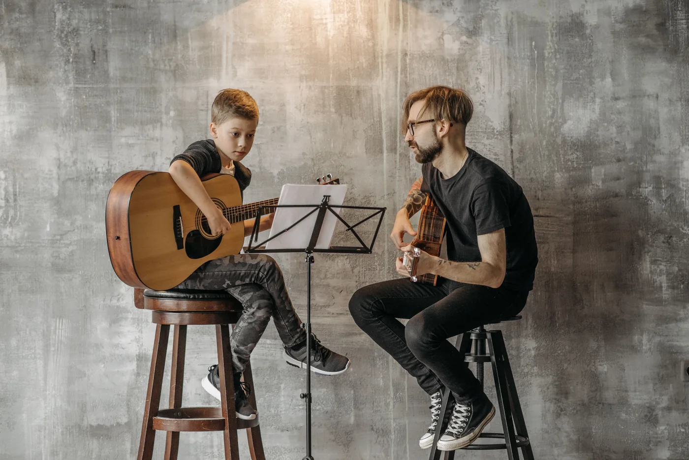 A child playing guitar with an adult instructor
